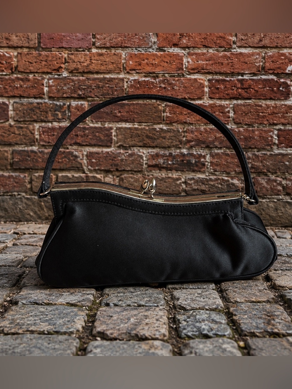 Black asymmetrical sloping kiss closure formal event purse.